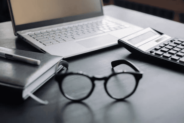 Laptop, calculator, notebook and glasses on a clean professional desk